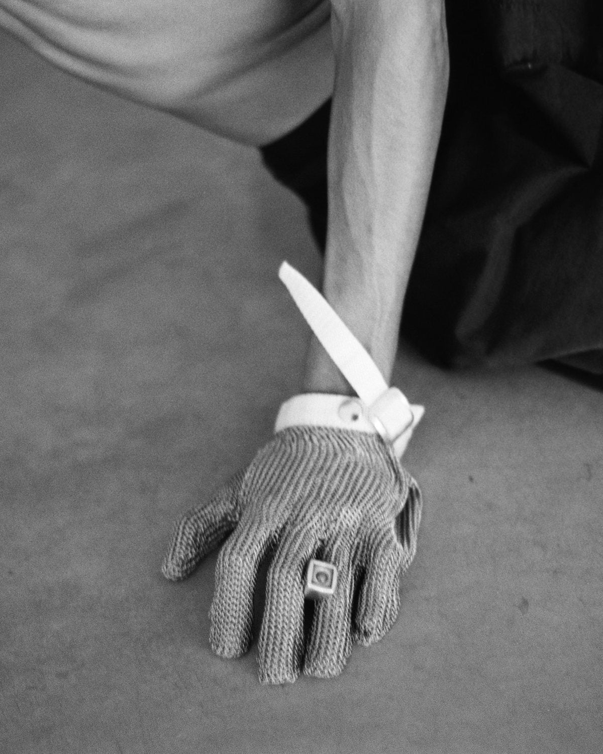Hand in a chainmail glove wearing a square silver ring